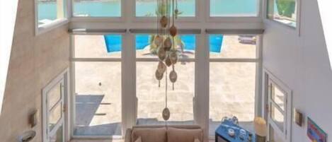 A spacious living area with a large window overlooking a pool and a scenic view.