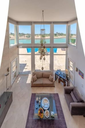 Un amplio salón con un gran ventanal que da a una piscina y vistas panorámicas.