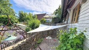 Een tuinpatio met een tafel, stoelen, een pergola en een stenen muur.