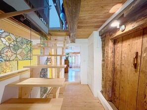 Eine Holztreppe führt zu einem Raum mit einer Holztür und einem Buntglasfenster.