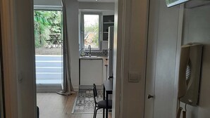 A doorway leading to a room with a dining area, a kitchen, and a view of the outdoors. - Charming Studio with Terrace and Garden in the 17th arrondissement, 09 (Paris)