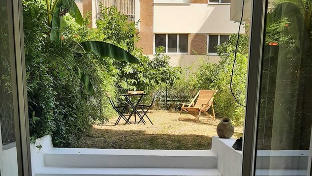 A view of a staircase leading to a backyard with a table and chairs, a wooden chair, and a potted plant. - Charming Studio with Terrace and Garden in the 17th arrondissement, 09 (Paris)