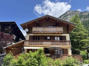 A multi-story wooden building with balconies, a covered entrance, and a mountainous backdrop. - 300m from ski slopes, 1st floor, tv, ski locker, 57m², Pralognan-la-Vanoise (Pralognan-la-Vanoise)