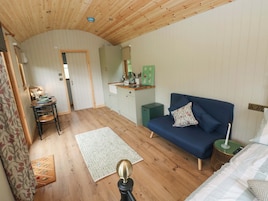 A room with a wooden ceiling, a sofa, a small table, a green cabinet, and a door leading to another room.