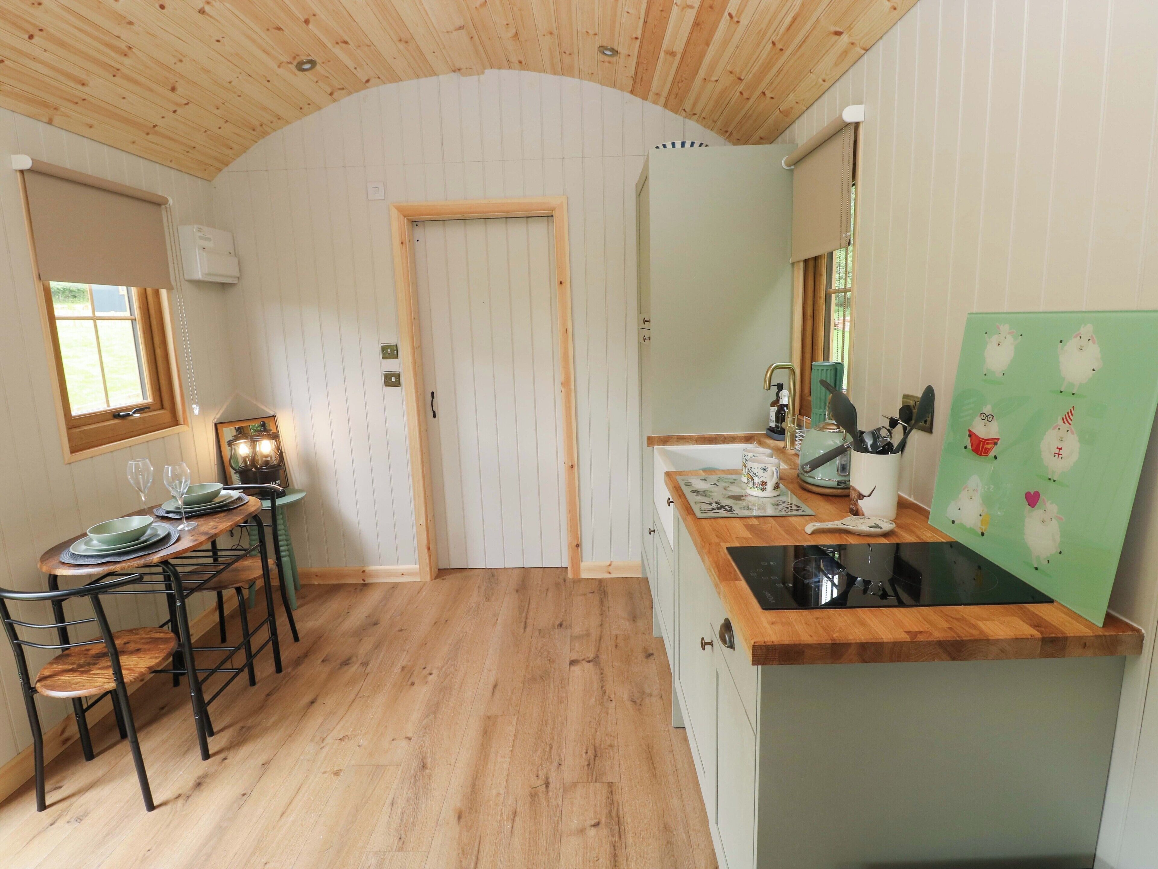 Una cocina compacta con encimeras de madera, un lavamanos y una zona de comedor con sillas y una mesa.