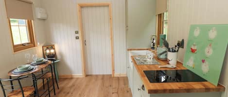 Una cocina compacta con encimeras de madera, un lavamanos y una zona de comedor con sillas y una mesa.