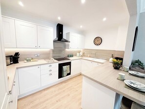 A modern kitchen with white cabinets, a black stove, and a wooden countertop.
