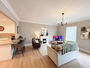A modern living room with a fireplace, a dining area, and a kitchen.