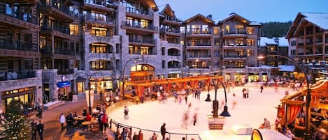 Et hotel med flere etager og en central gårdsplads med skøjtebane, udendørs siddepladser og en madbod.