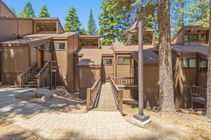 A modern building with multiple levels, a central staircase, and a surrounding natural landscape. - Trailside Condo | Steps to Shuttle & Village (Truckee)