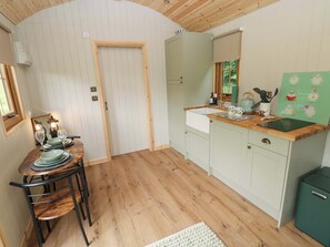 Una cocina compacta con piso de madera, un área de comedor con mesa y sillas, y un refrigerador verde.