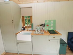 Cocina compacta con pileta, mesón de madera y ventana con vista a la vegetación.
