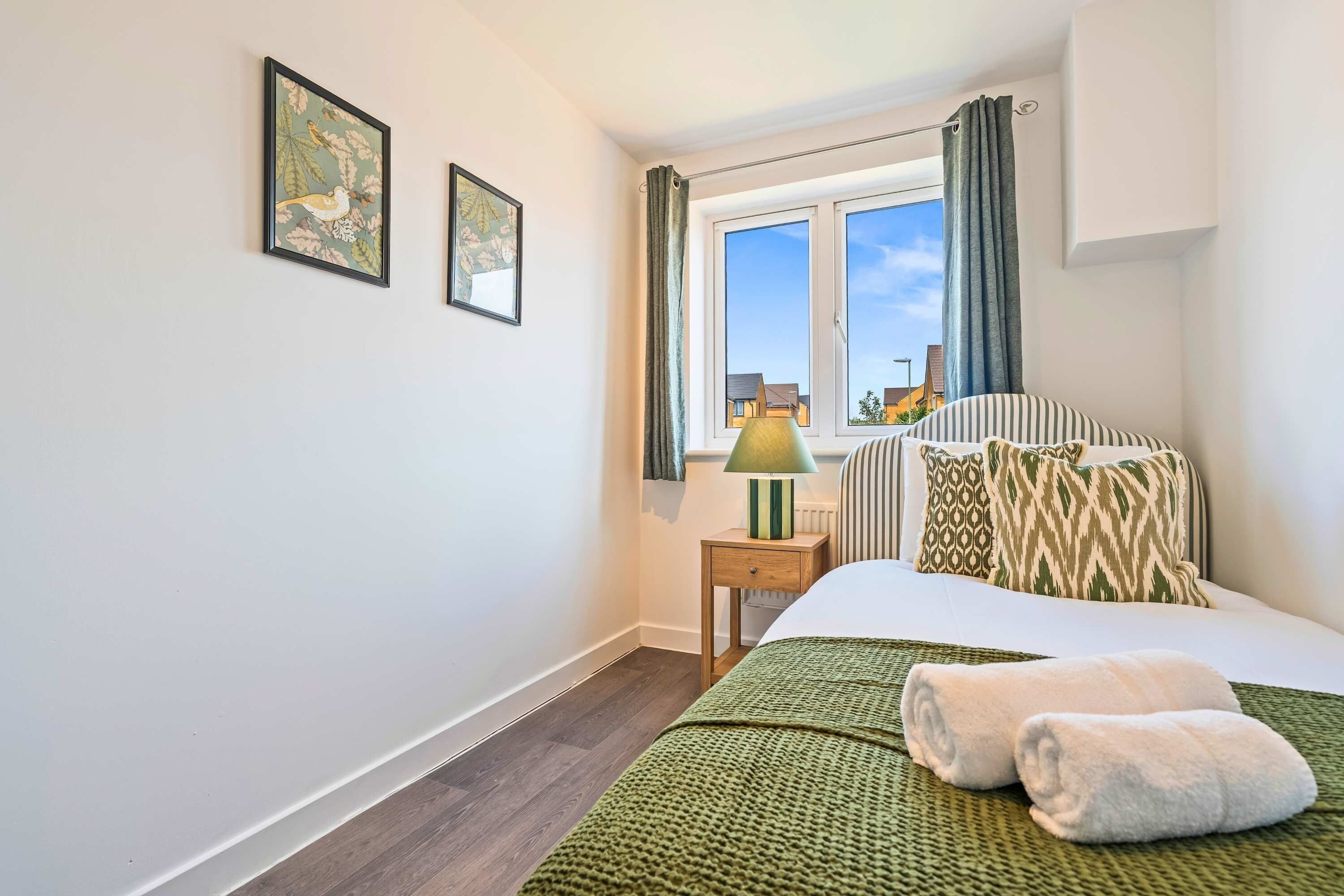 Une chambre à coucher avec un lit, une table de chevet, une lampe et deux tableaux encadrés accrochés au mur.