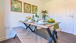 Un coin repas avec une table en bois, des chaises, un banc et une porte blanche.