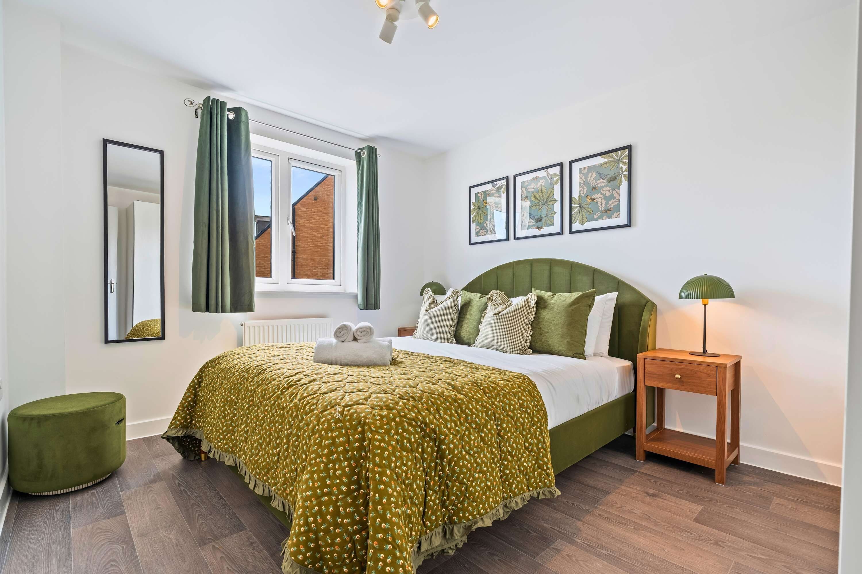 Une chambre à coucher avec un lit, une table de chevet, une lampe, une fenêtre avec des rideaux et un radiateur.