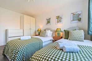 A hotel room with two beds, a wardrobe, and three wall-mounted artworks.
