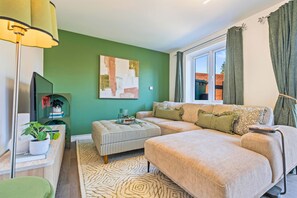 A modern living room with a sofa, ottoman, and a painting on the wall.