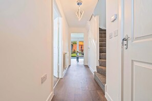 A hallway with a wooden floor, white walls, and a staircase with carpeted steps. - 4 BR House with Private Garden, 2X FREE Parking (Basingstoke)