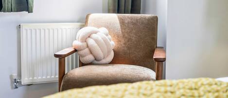 A room with a chair, a radiator, and a bed with a blanket.