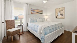 Una camera da letto con un letto, una sedia, una ventola a soffitto e opere d'arte alle pareti.