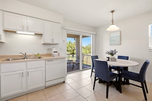 A kitchen with white cabinets, a sink, and a dining area with a table and chairs. - Spacious duplex, dog friendly & full kitchen (Englewood)