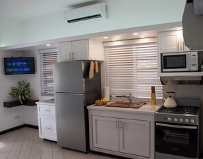 A compact kitchen with a refrigerator, microwave, stove, and a flat-screen TV. - Bright Studio w/ Workspace & Marina View in Cas en Bas, Gros Islet (Gros Islet)