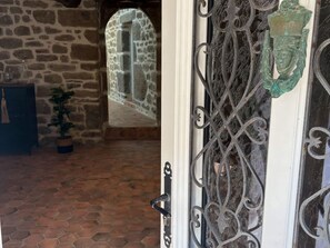 Eine Steinsäule, ein Blumentopf und eine Tür mit aufwendiger Metallverzierung.