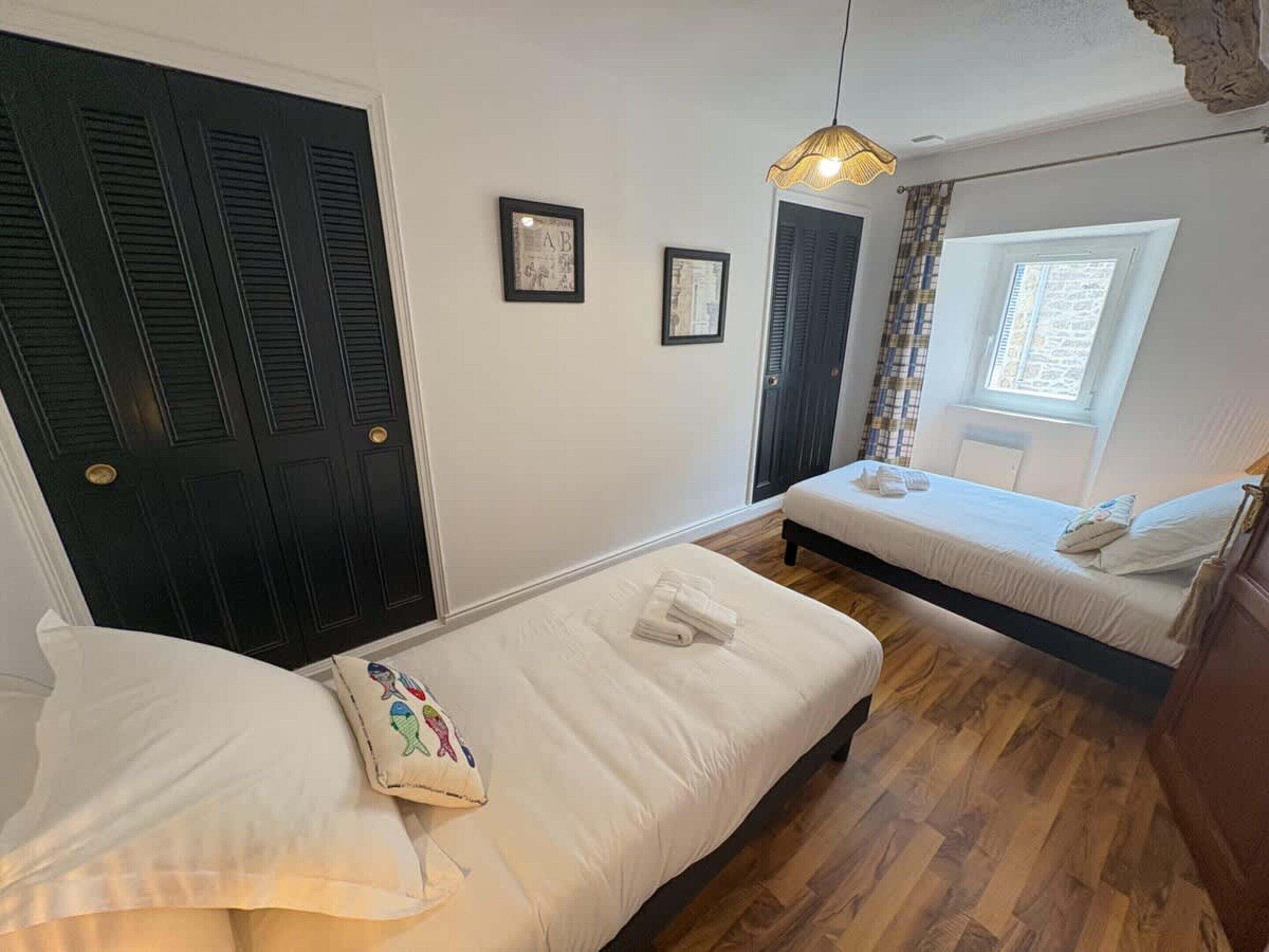 A bedroom with two beds, a window, and a door with shutters.