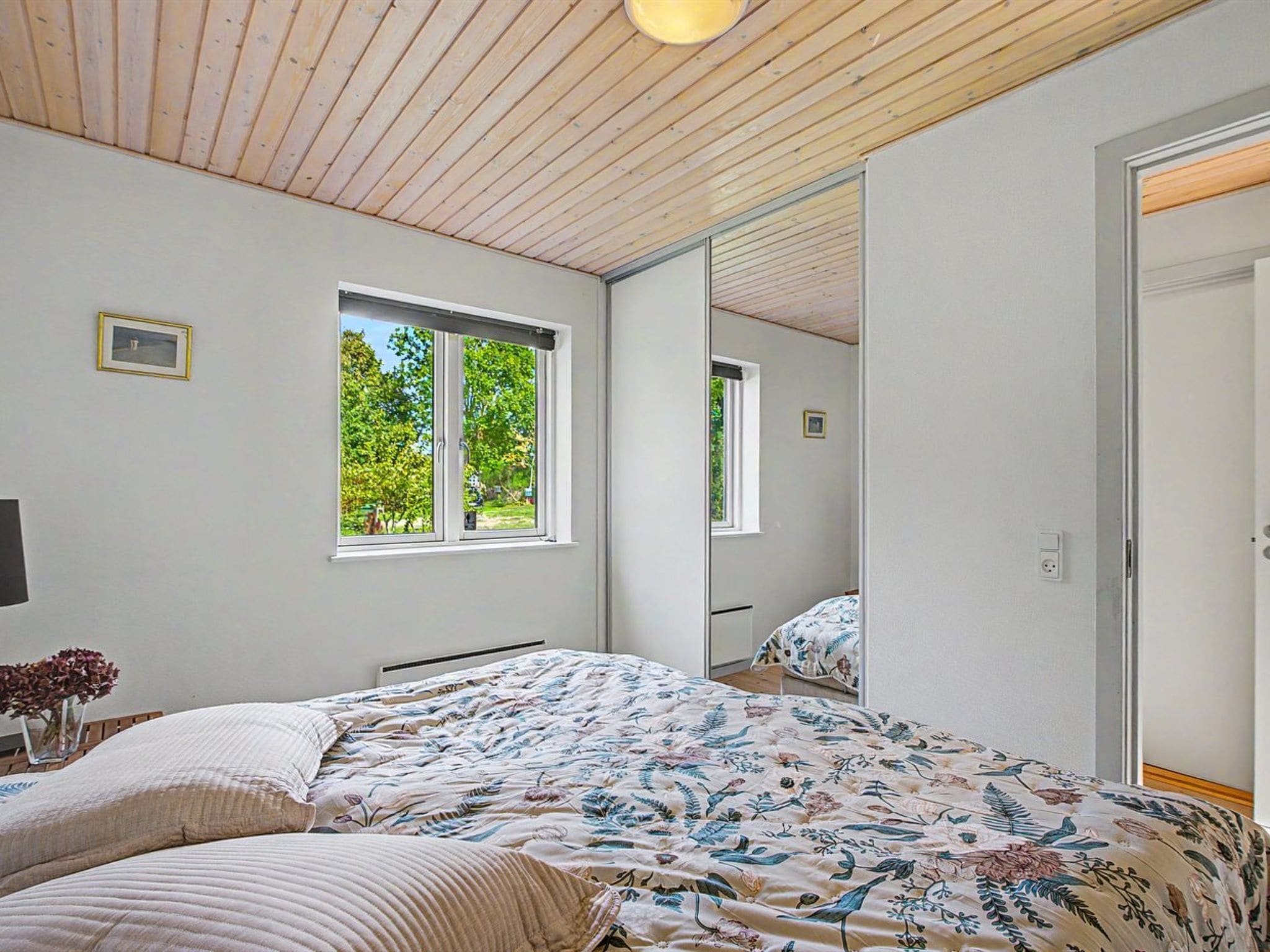A bedroom with a bed, a window, and a mirror.