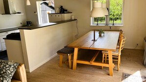 Una cocina moderna con una isla de madera, una mesa de comedor con sillas y un ventanal con vistas a la vegetación.