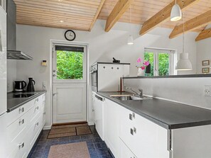 A modern kitchen with white cabinetry, a built-in oven, and a window with a view of greenery.