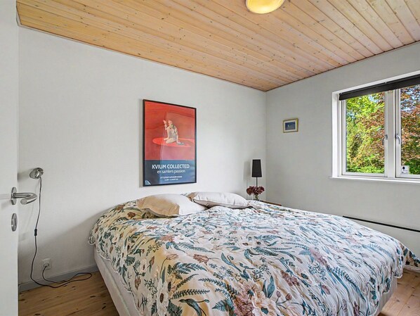 A bedroom with a bed, a poster on the wall, a window, and a door.