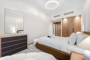 A modern hotel room with a large bed, a bedside table, a wardrobe, and a round ceiling light. - Free housekeeping visits during your stay - StayShort - Stunning 1BR Retreat in JVC that Sleeps 2! (JVC)