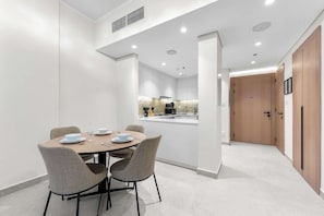 A modern kitchen with white cabinets, a central island, and a dining area with a round table and four chairs. - Free housekeeping visits during your stay - StayShort - Stunning 1BR Retreat in JVC that Sleeps 2! (JVC)