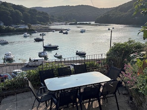 A riverside view with boats, a table, chairs, and a railing. - Overdale (Looe)