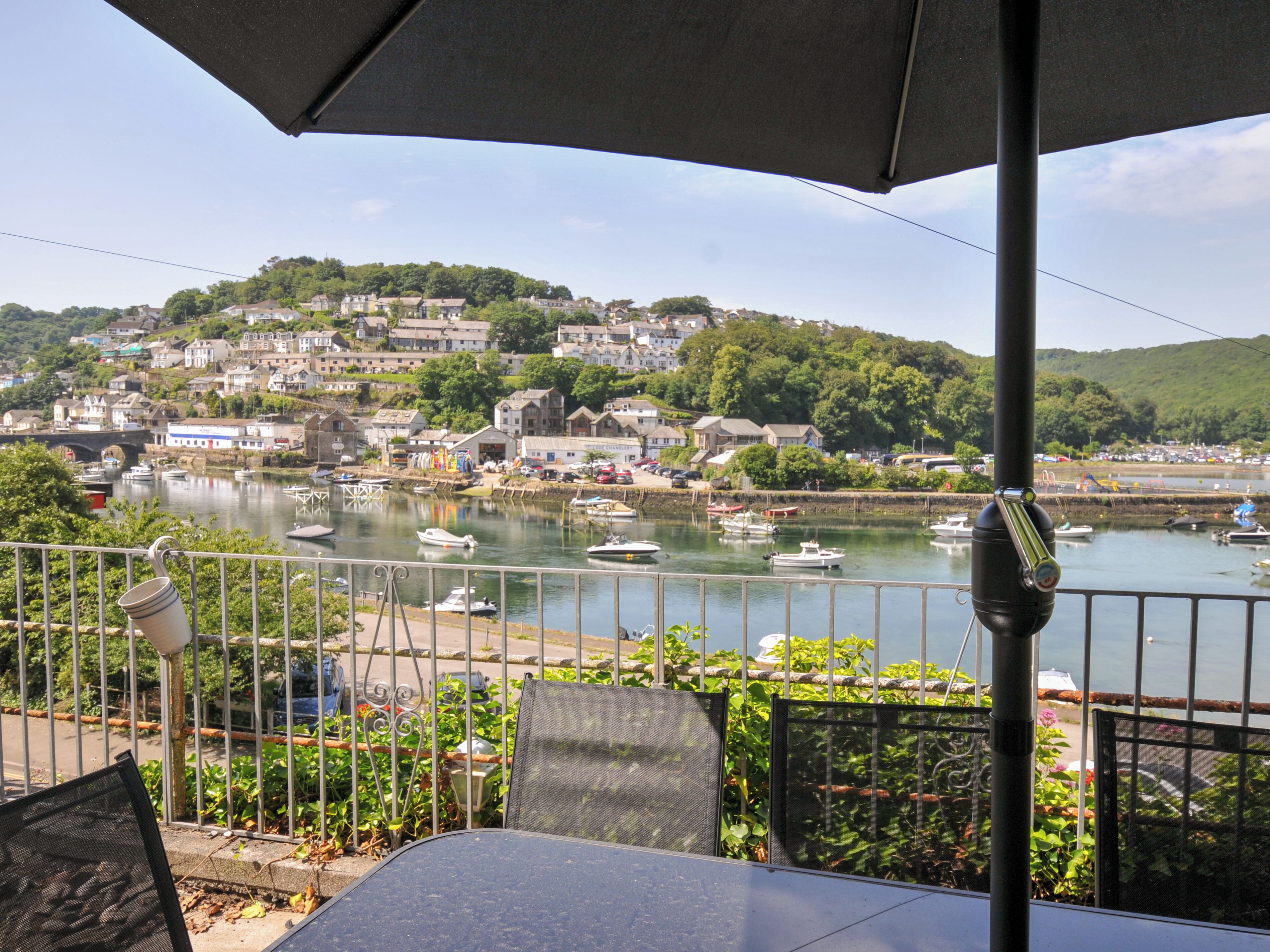 A balcony with a view of a harbor, boats, and a hillside town.
