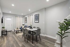 Ein modernes Wohnzimmer mit Essbereich, grauen Wänden und Holzboden.