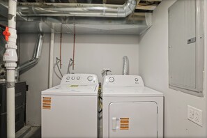 Ein Waschraum mit zwei weißen Waschmaschinen, einem Lüftungsschacht und einem Stauraumschrank.