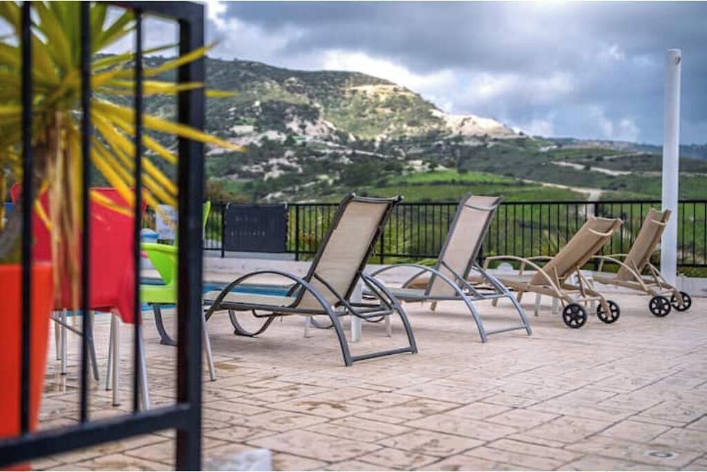 Outdoor lounge chairs, a tiled patio, and a mountainous landscape in the background.