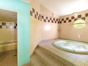 Ein Badezimmer mit Badewanne, gefliesten Wänden, einem Fenster und einer Dusche.