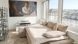 A bedroom with a bed, a TV, a window, and a view of buildings. - Mirami Apartement with Private Parking and Basellandcards (Allschwil)