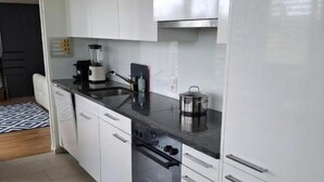 A modern kitchen with white cabinets, a black countertop, a built-in oven, and a coffee maker. - Mirami Apartement with Private Parking and Basellandcards (Allschwil)