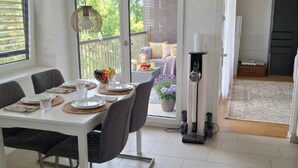 A dining area with a table set for four, a sliding glass door leading to a balcony, and a coffee machine. - Mirami Apartement with Private Parking and Basellandcards (Allschwil)