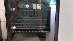 Kompakti jääkaappi, jossa on sisäänrakennettu jääpalakone, sekä vedenkeitin ja kahvinkeitin sen päällä.