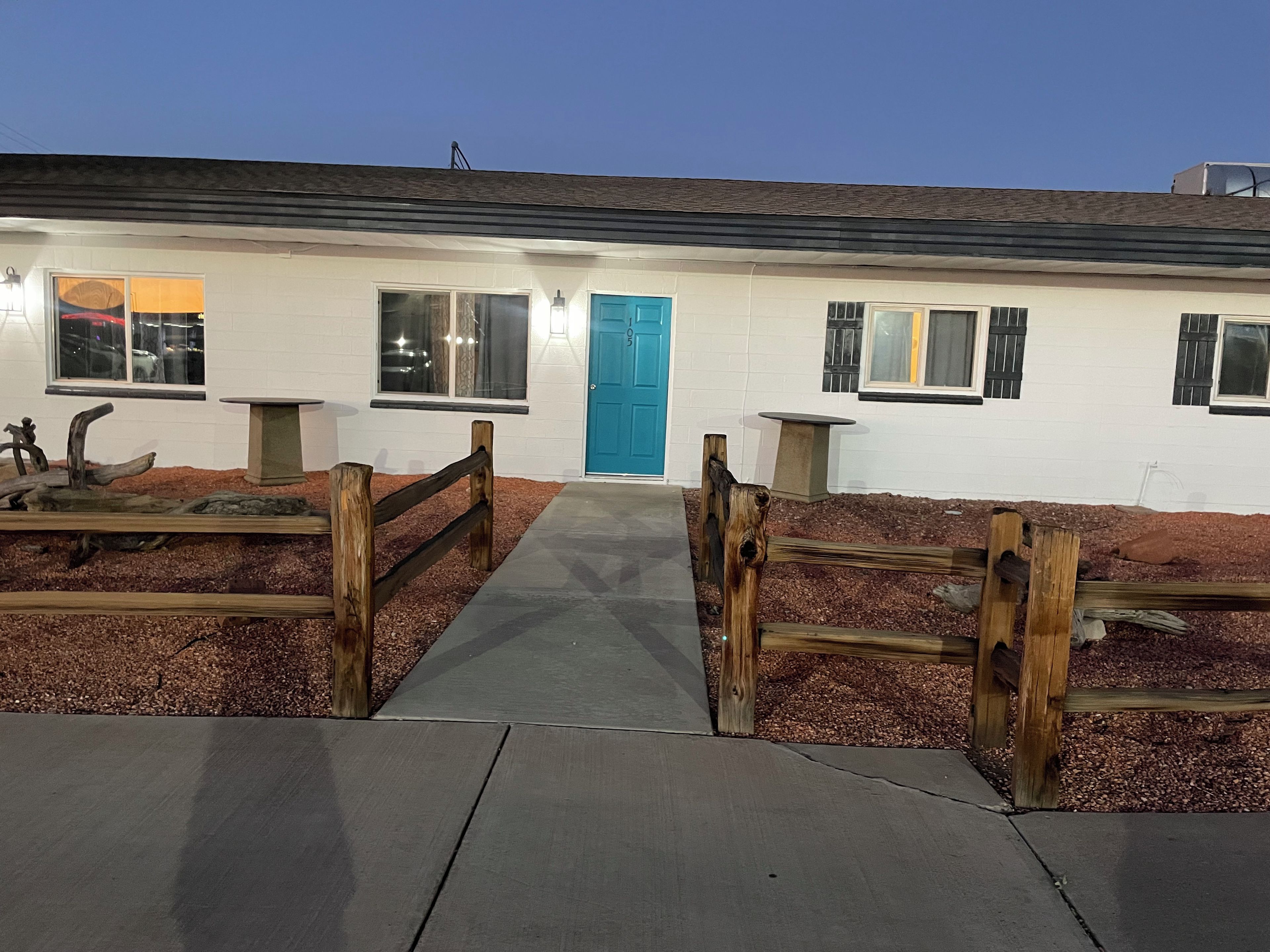 A building with a blue door, windows, and a concrete pathway leading to the entrance.