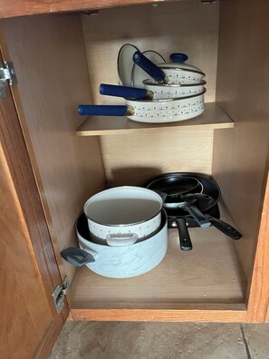 Un meuble de cuisine doté de deux étagères contenant des ustensiles de cuisine, notamment une casserole et une poêle.