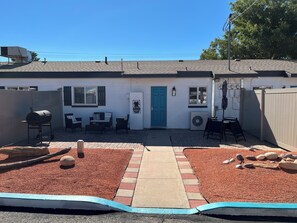 A residential backyard with a barbecue grill, outdoor seating, a blue door, and a paved patio area. - Serene 2-bedroom apartment with AC in charming Page (Page)
