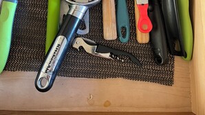A drawer with kitchen utensils including spatulas, a grater, and a can opener.