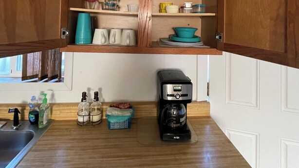 A kitchen with wooden cabinets, a coffee maker, and various kitchen items.