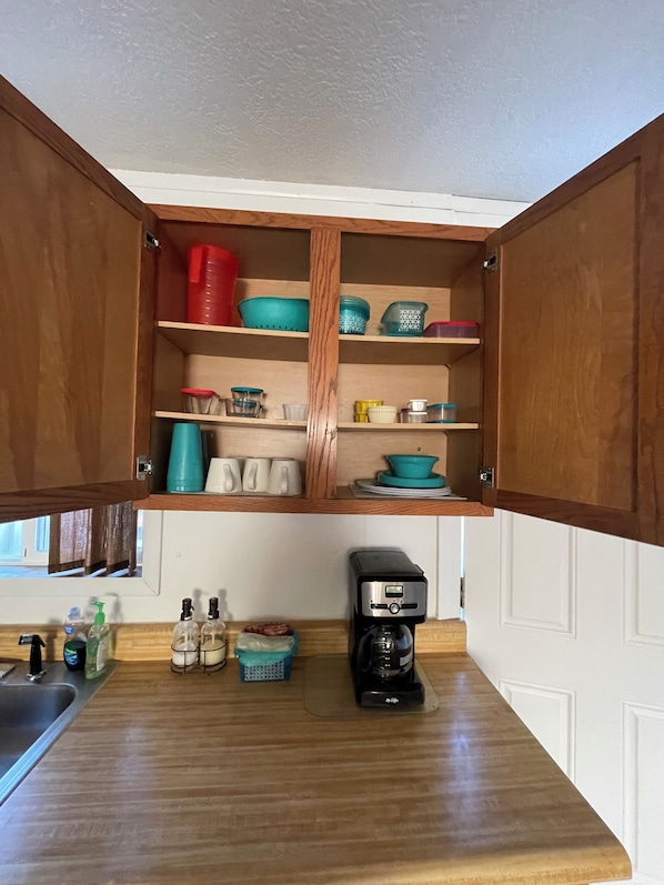 A kitchen with wooden cabinets, a coffee maker, and various kitchen items.